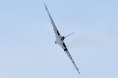 Low angle view of airplane flying against clear blue sky