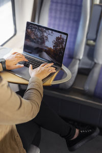 Mid section of woman using laptop during train journey