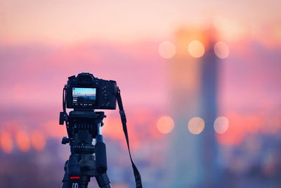 Close-up of camera against sky during sunset