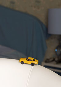 Close-up of yellow toy car on sofa at home