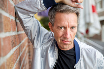 Portrait of man standing by brick wall