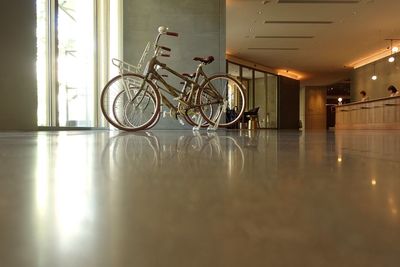 Bicycles on floor against illuminated wall