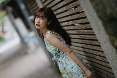 Portrait of young woman standing by railing