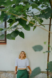 Portrait of young woman standing against wall