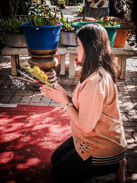 Woman holding incense and plant in temple