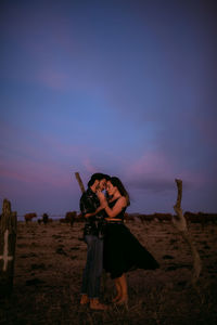 Woman standing on field against sky during sunset