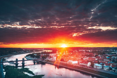 Bridge over river in city against orange sky