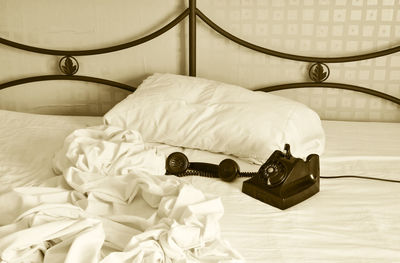 Close-up of rotary phone on bed at home