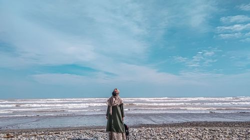 Woman standing on beach against sky