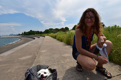 Portrait of woman with dog sitting against sky