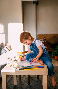 Small child at home at the children's table draws with felt-tip pens.