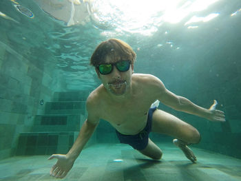 Portrait of shirtless man swimming in pool