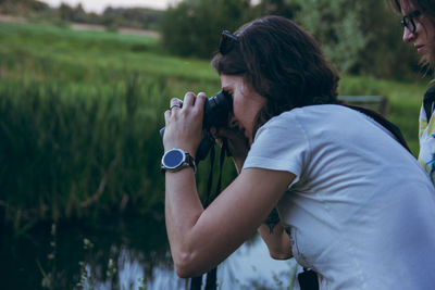 Side view of man photographing on field