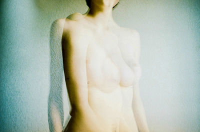 Blurred motion of shirtless woman standing against wall