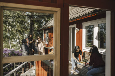 Female friends enjoying dinner party at porch seen from window