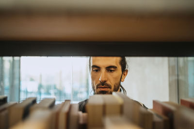 Young man searching book in library at university