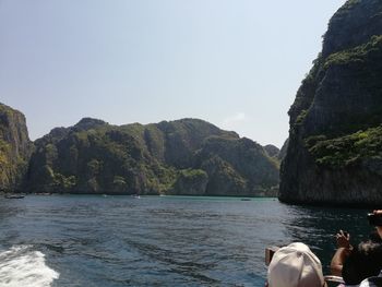 Scenic view of sea by mountains against clear sky