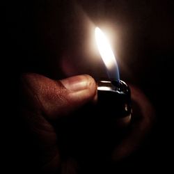 Close-up of hand holding burning candle