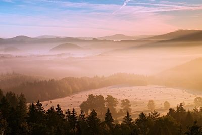 Pink daybreak in hilly landcape. autumn misty morning in beautiful hills. peaks of hills in mist