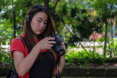 Young woman photographing against trees