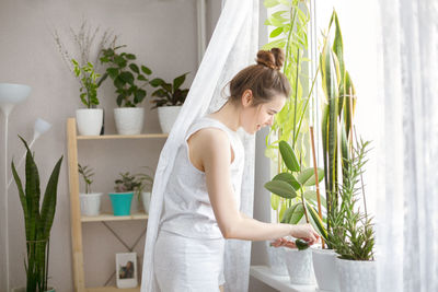 Side view of woman standing by potted plant