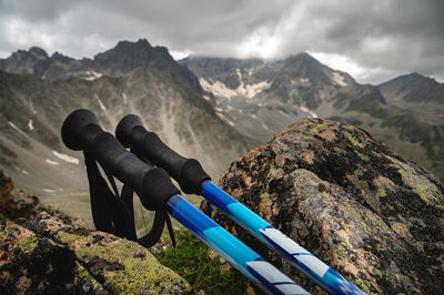 Trekking poles close-up, lie on a stone overgrown with grass, in summer, against the backdrop of