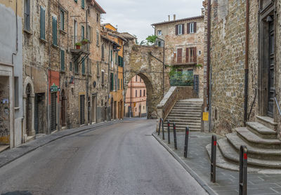 Empty road amidst buildings against sky in city