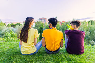 Rear view of people sitting on field