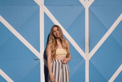 Portrait of smiling woman standing against door