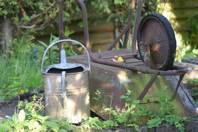 Close-up of old watering can and wheel barrow