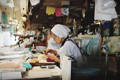 Side view of senior woman working in factory