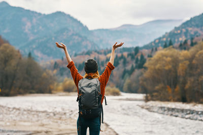 Rear view of man with arms outstretched standing on mountain