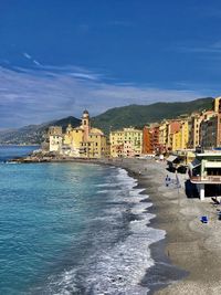 Buildings by sea against blue sky