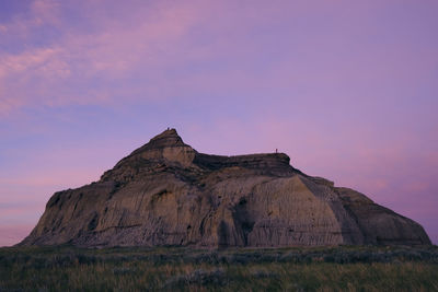 Muddy formations on field against sky during sunset