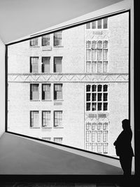 Rear view of man standing by building against sky