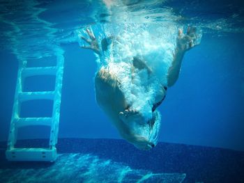Underwater view of person jumping into swimming pool