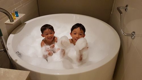 High angle portrait of cheerful brothers in bathtub