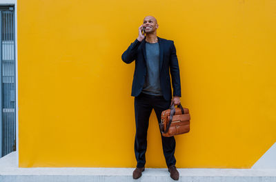 Young man standing against yellow wall