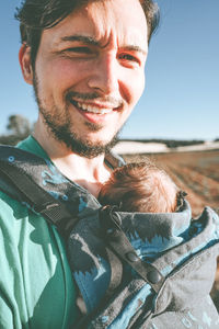 Portrait of smiling man with baby standing outdoors