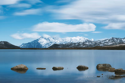 Scenic view of lake and snowcapped mountains against cloudy sky