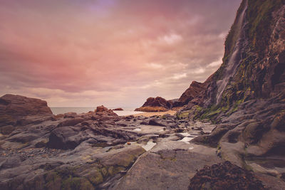 Rock formations in sea against sky during sunset