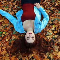 High angle view of young woman lying down on autumn leaves