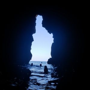 Silhouette rock formations in sea against sky