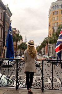 Rear view full length of woman standing by street in city