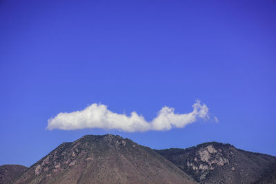 Low angle view of volcanic mountain against blue sky