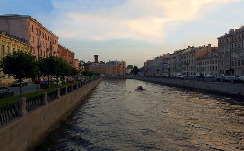 Canal amidst buildings in city against sky