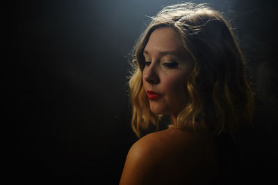Portrait of woman looking away against black background