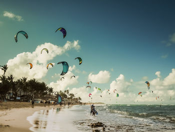 People kiteboarding at beach against sky