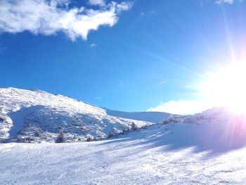 Scenic view of snowcapped mountains against blue sky on sunny day