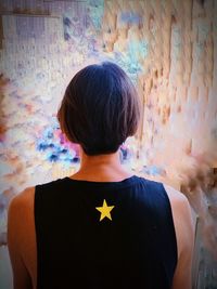 Rear view of boy standing against wall at home